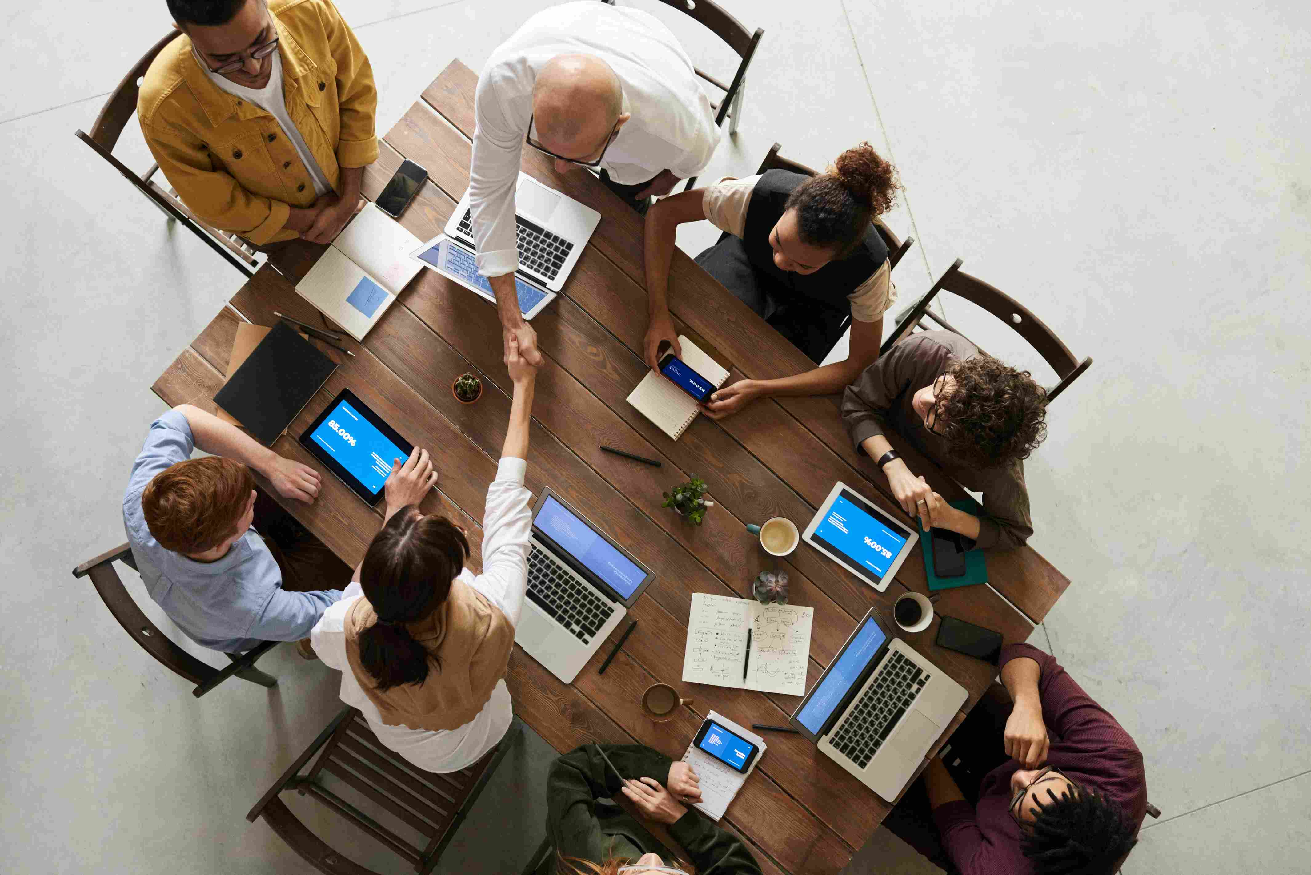 A imagem contém uma mesa com pessoas fazendo aperto de mão cruzado, levando em consideração a colaboração da equipe e planejamento da lutruvials.